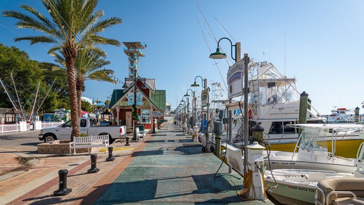 A street with boats and palm trees in Destin, Florida