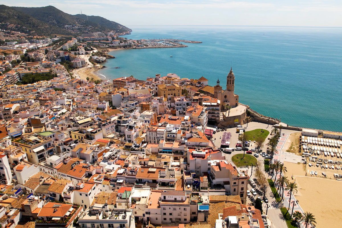Aerial view of Sitges coastal village and Iglesia de San Bartolomé y Santa Tecla during a sunny day