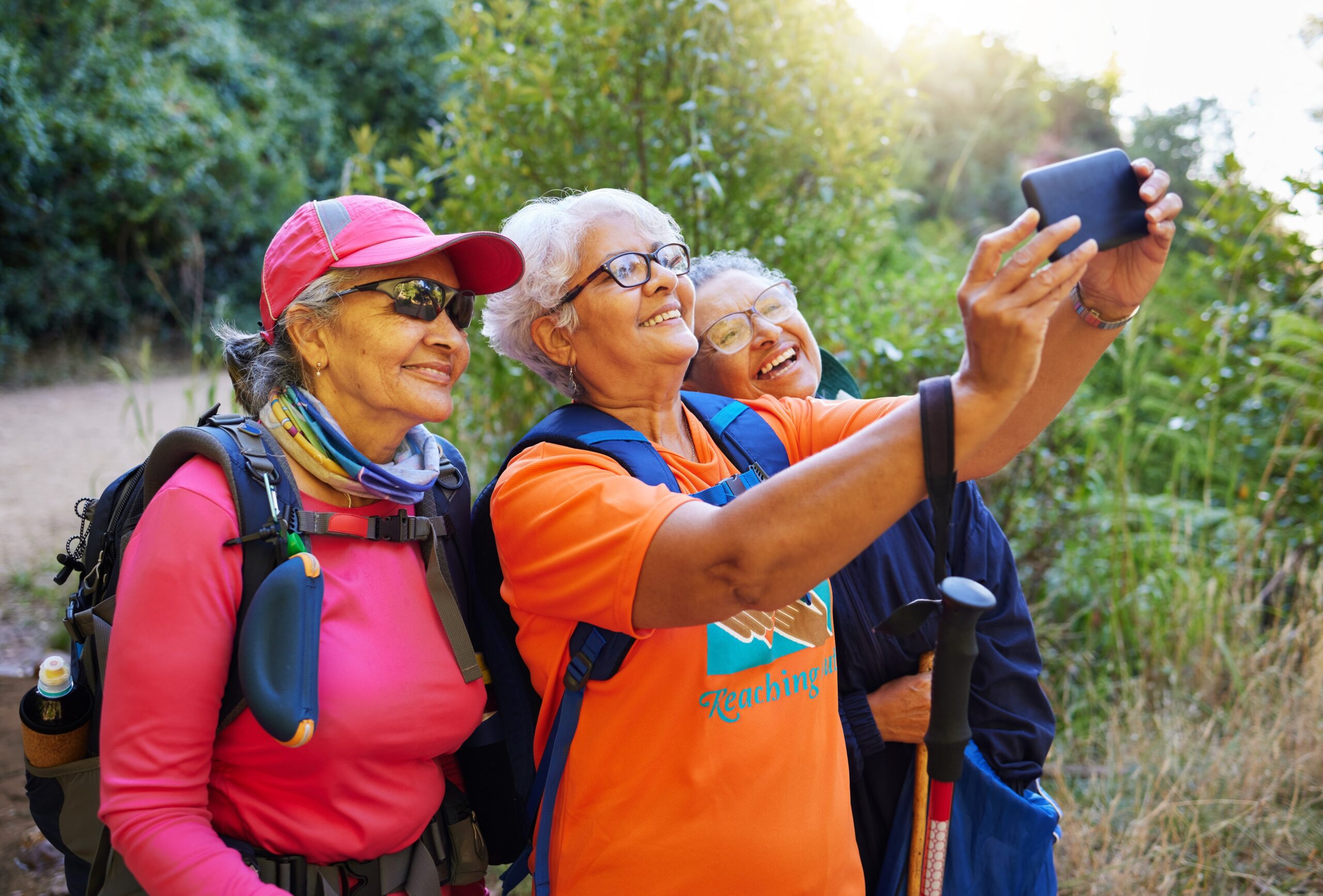 three smiling older women in travel hiking outdoors