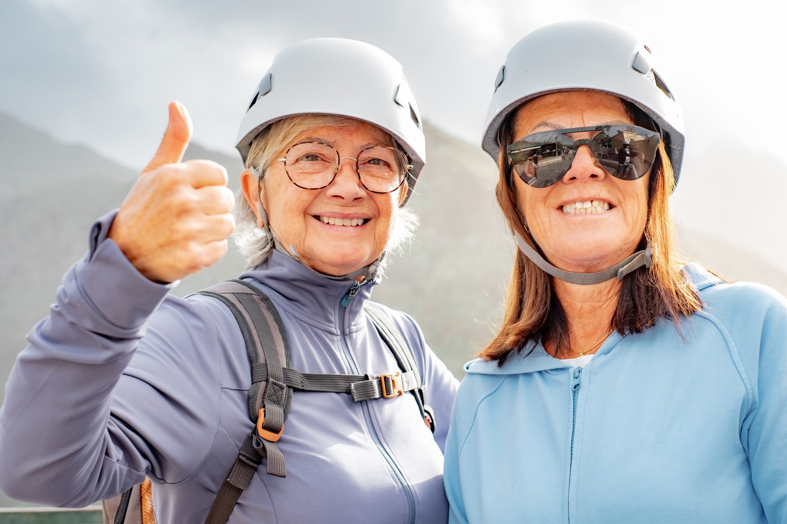 smiling older women hiking on mountain thumbs up