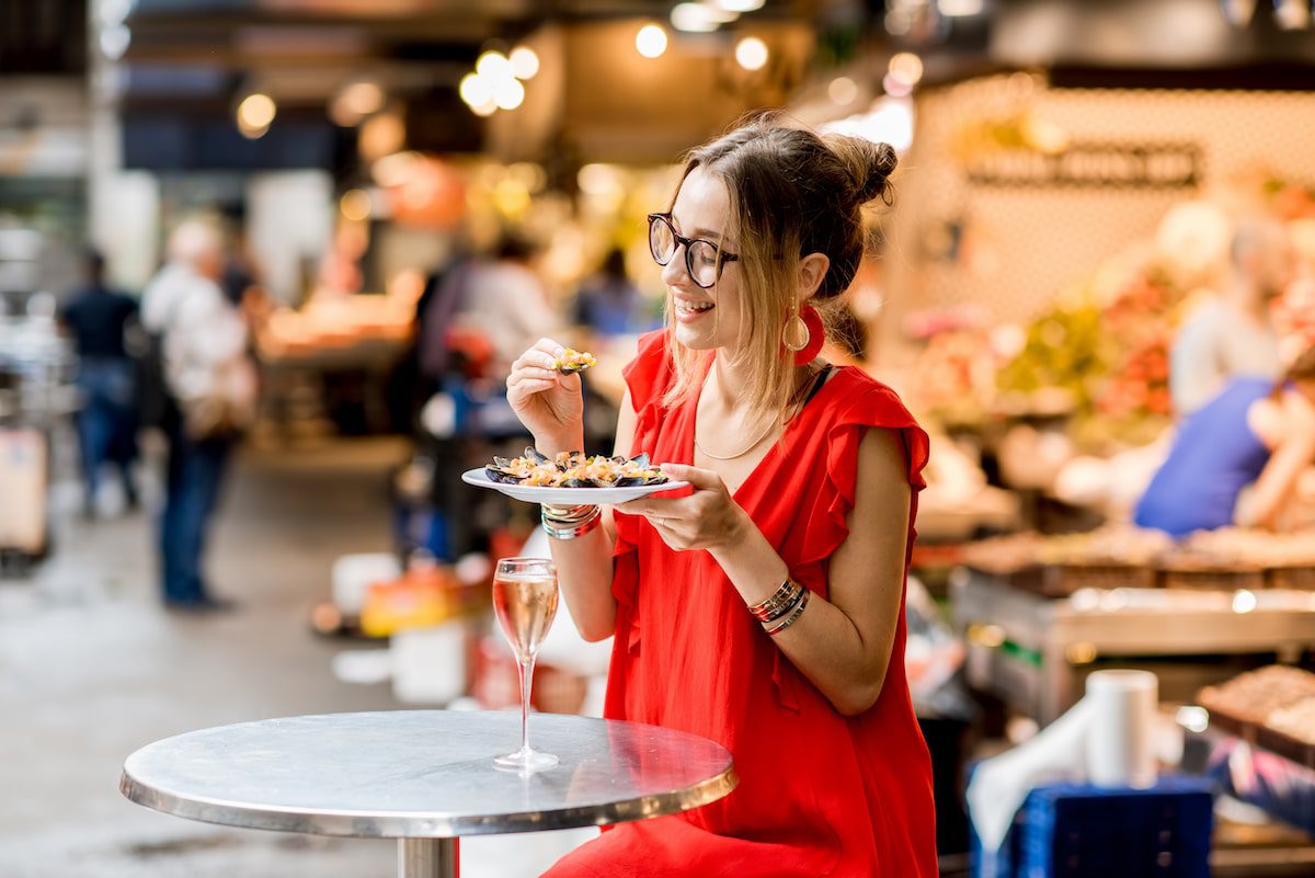 Woman eating mussels at the food market on a food tour.