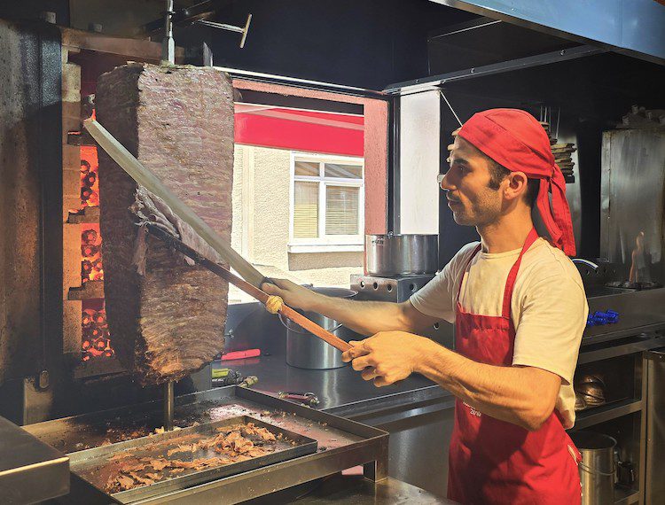 A man cutting meat from a kebab spit in a shop in Istanbul