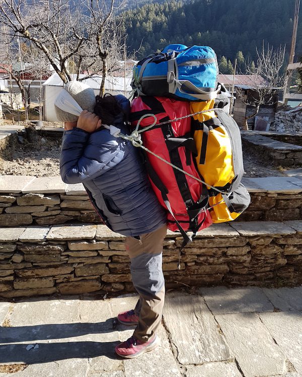 Kumari easily lifts 25kg of bags using a tumpline strap