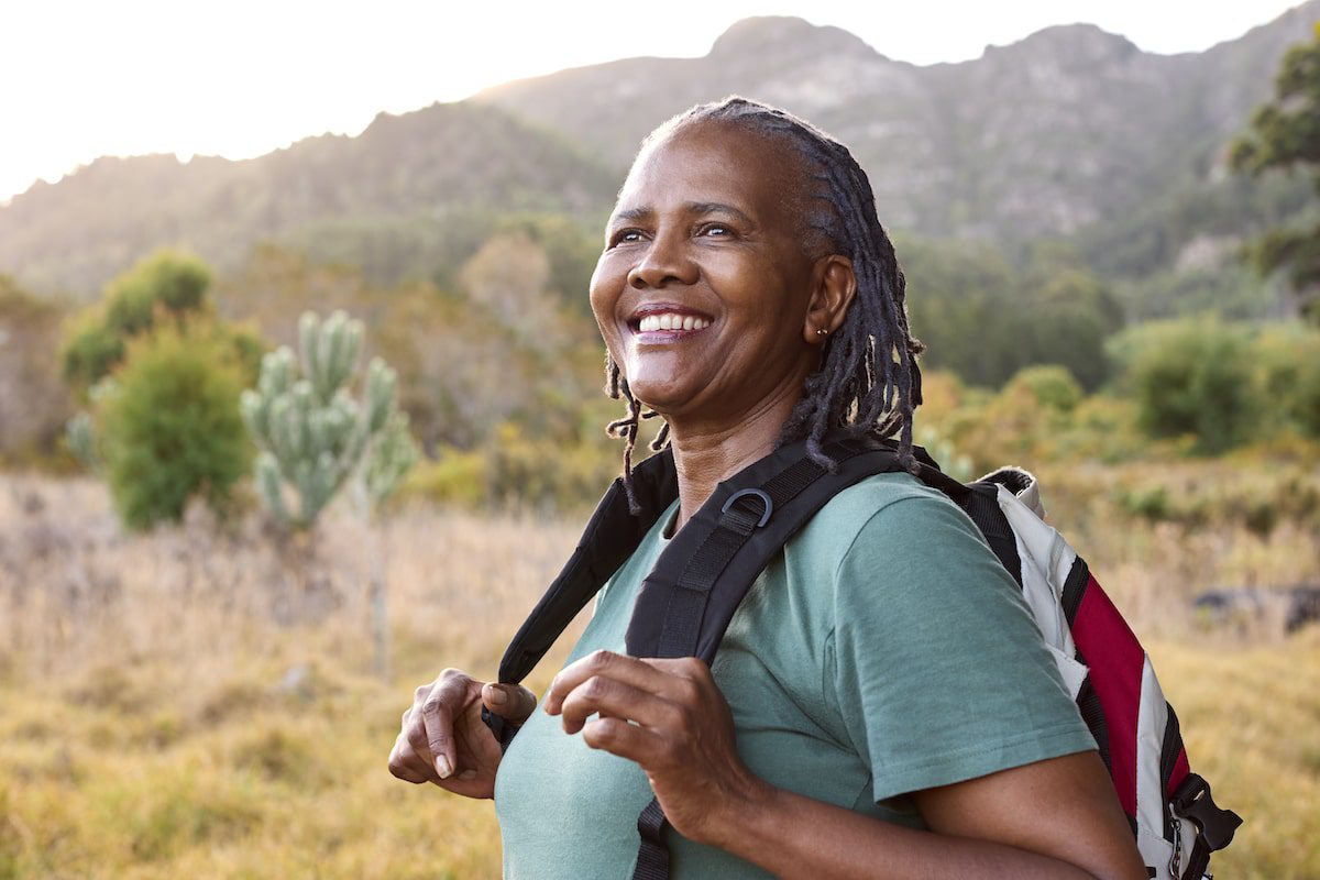 Portrait of active senior woman with backpack going for a hike in countryside