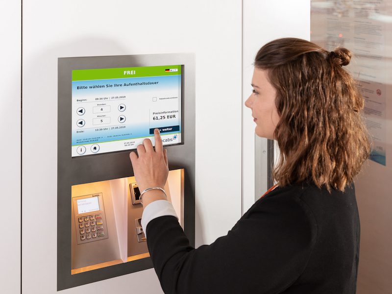 A woman books a room at NapCab in an airport in Germany