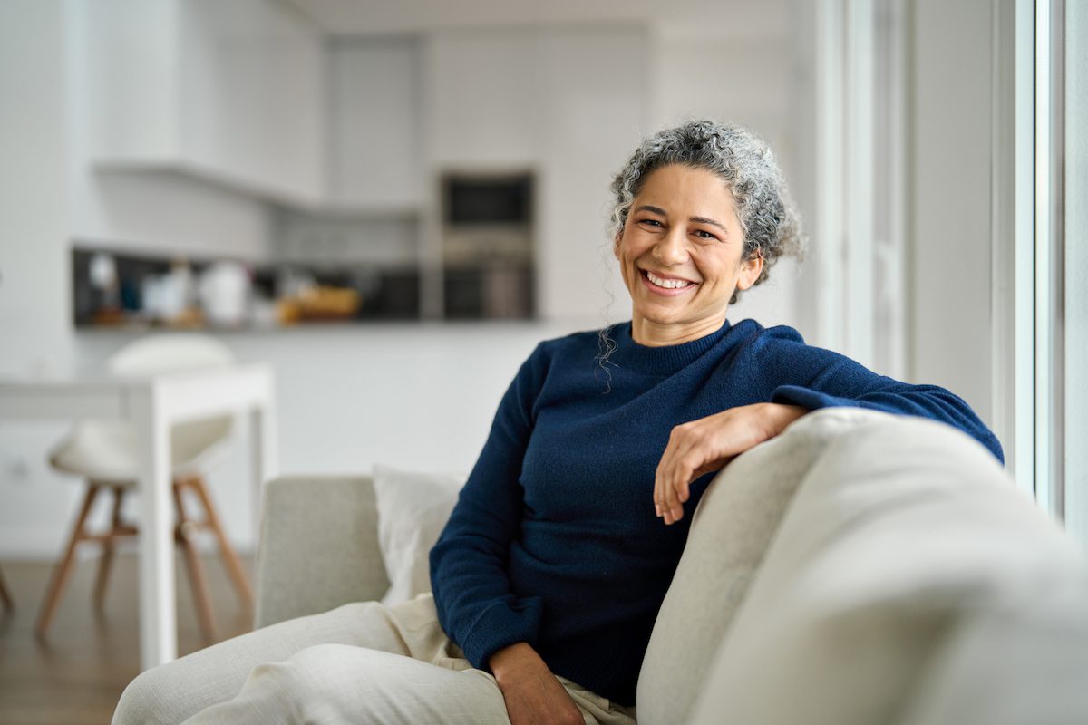 Happy middle aged woman sitting on comfy sofa in living room on a home exchange