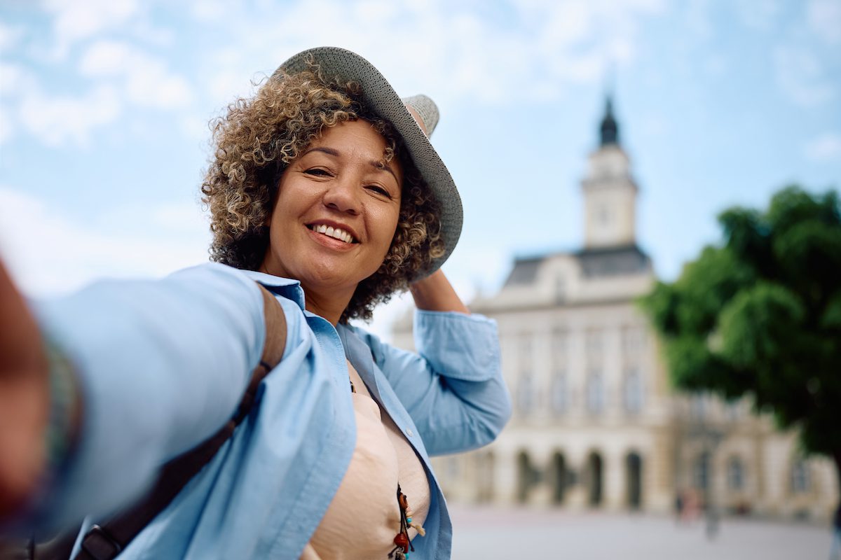 Carefree woman having fun while taking selfie during her travel and looking at camera.