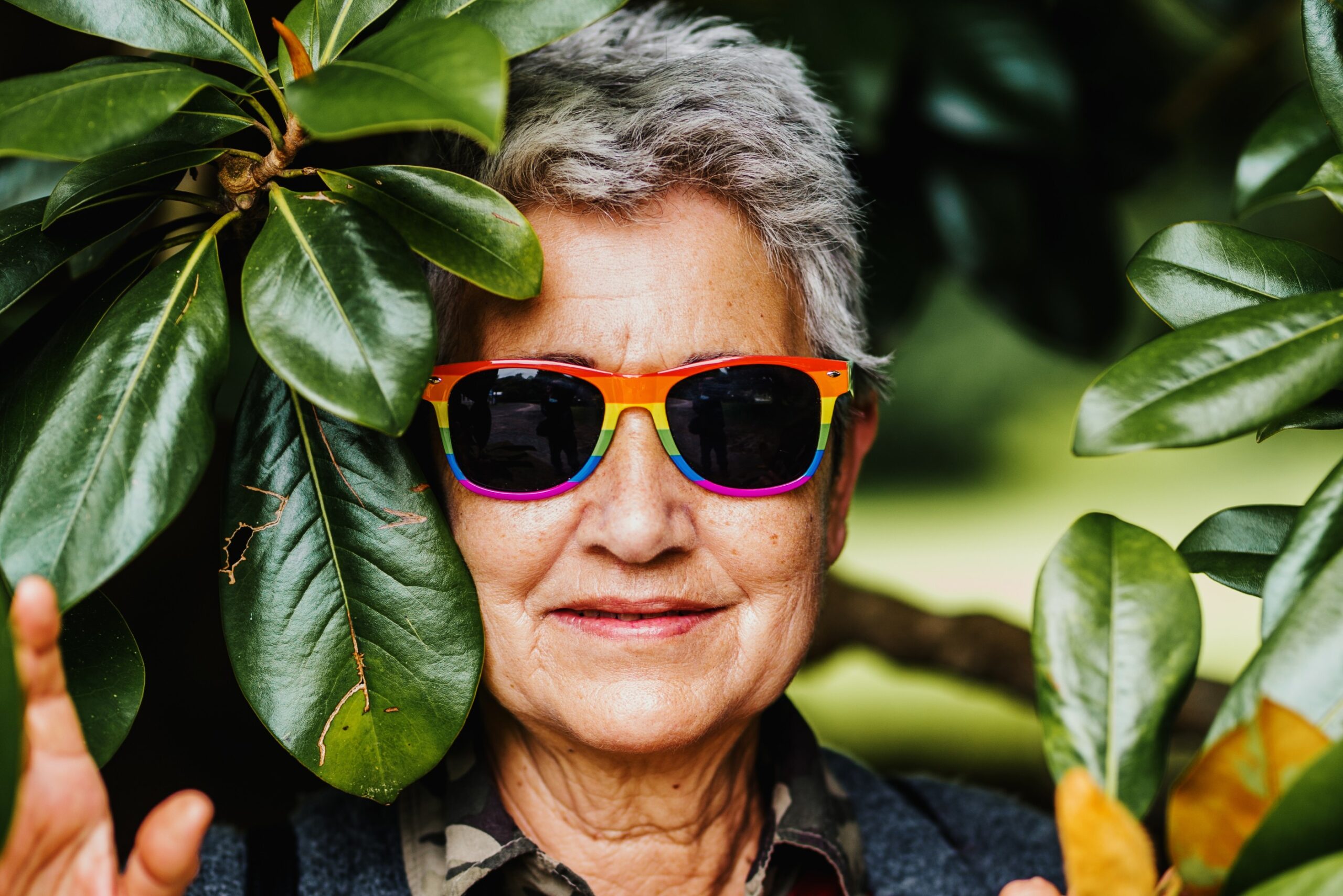 LGBTQ+ older woman smiling with rainbow glasses