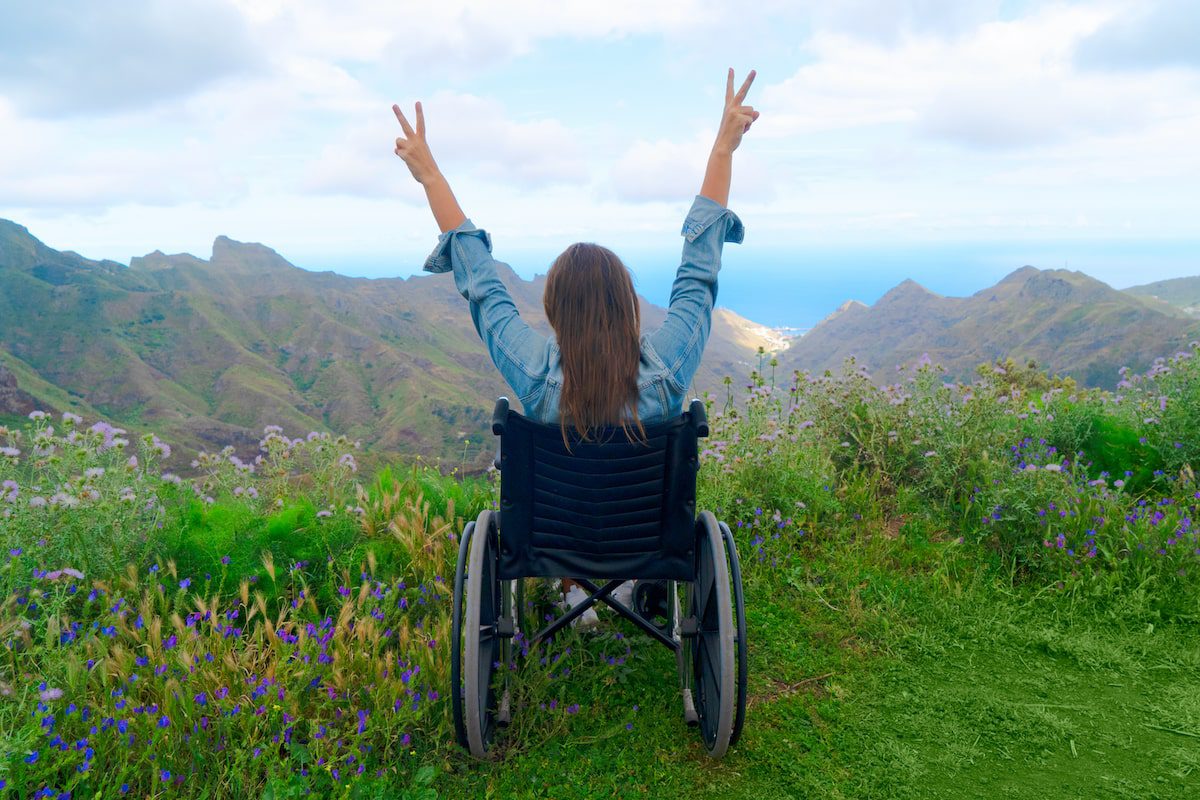 Woman in wheelchair on mountain hill enjoying view