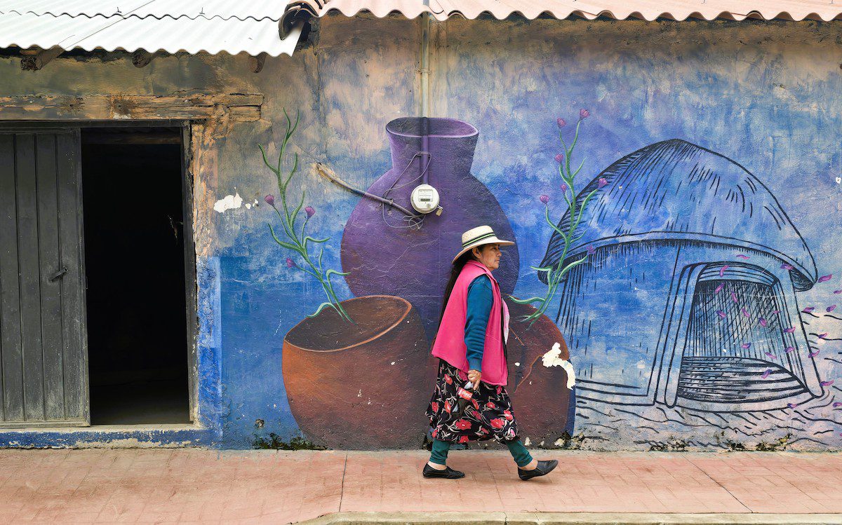 A woman walks past a mural in Tecometepec