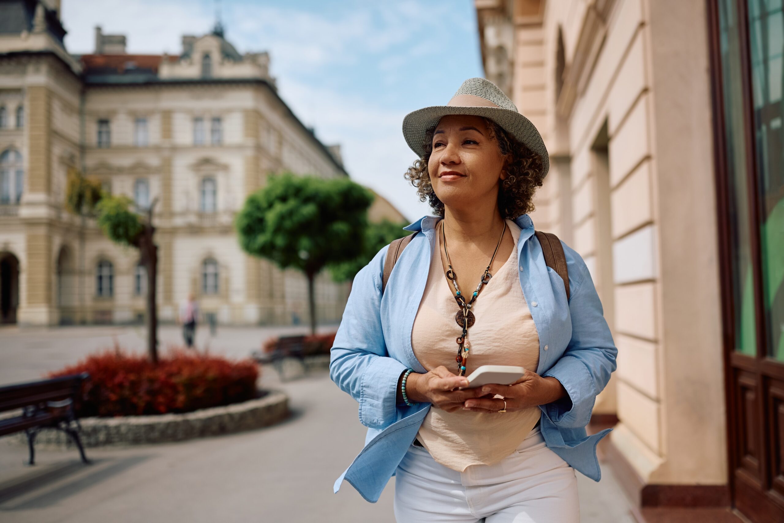 Smiling female traveler enjoying in walk through the city. By drazenphoto