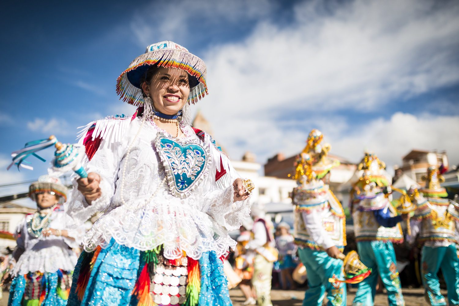 A jubilant dancer in traditional festive attire at a bright outdoor celebration.