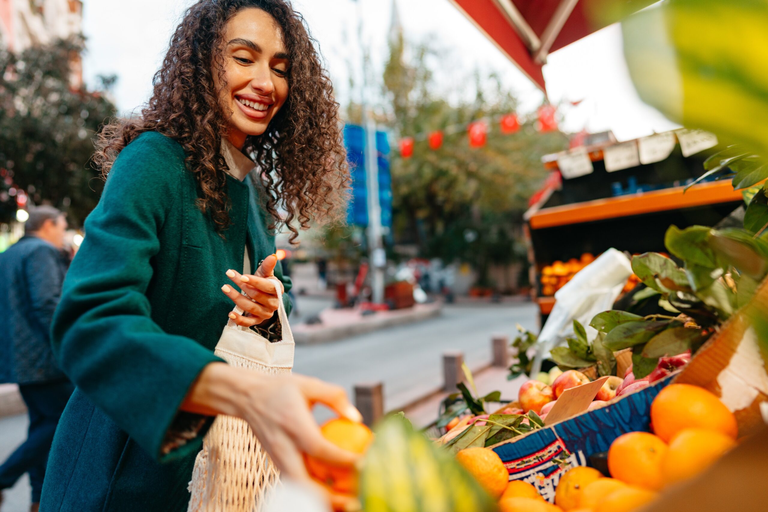 woman shopping for food at local farmers market stand