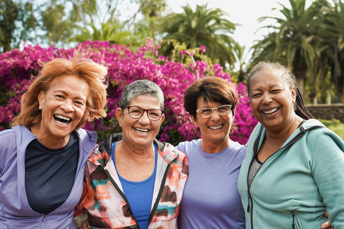 Group of happy diverse senior women hugging each other at city park