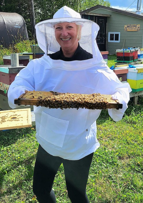 The author<br />
grasps a hive frame during a hands-on visit to Cormack Bee Company