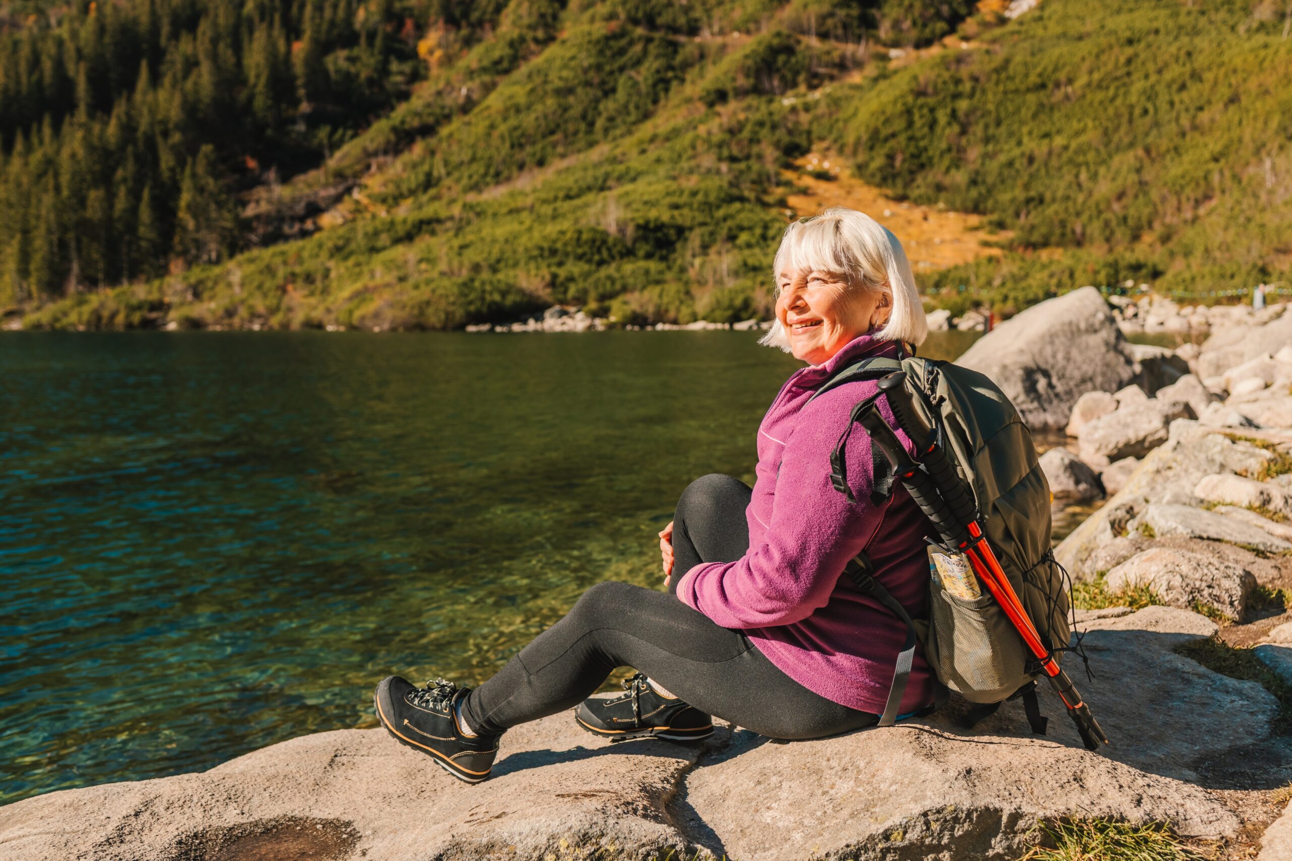 Senior 50s tourist woman with a backpack standing on top of the mountain and enjoy the beautiful by shiwork